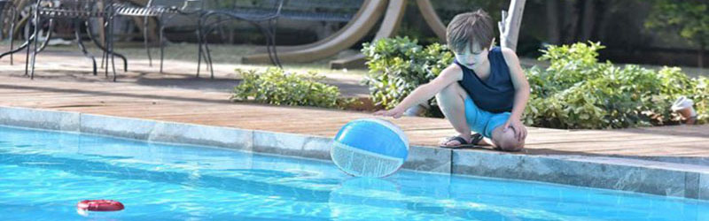 image of boy trying to get beach ball from side of pool